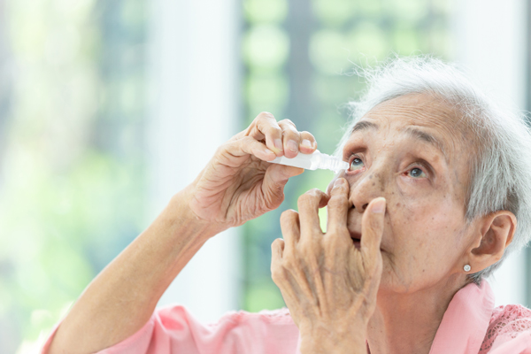 Older woman applying eye drops