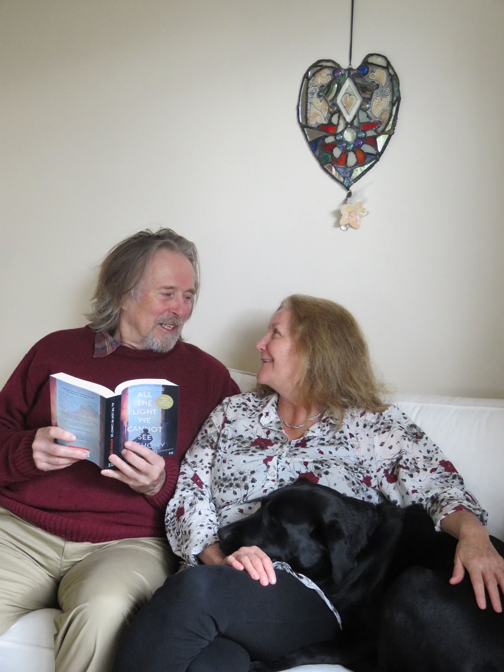 man reading book to woman and her guide dog