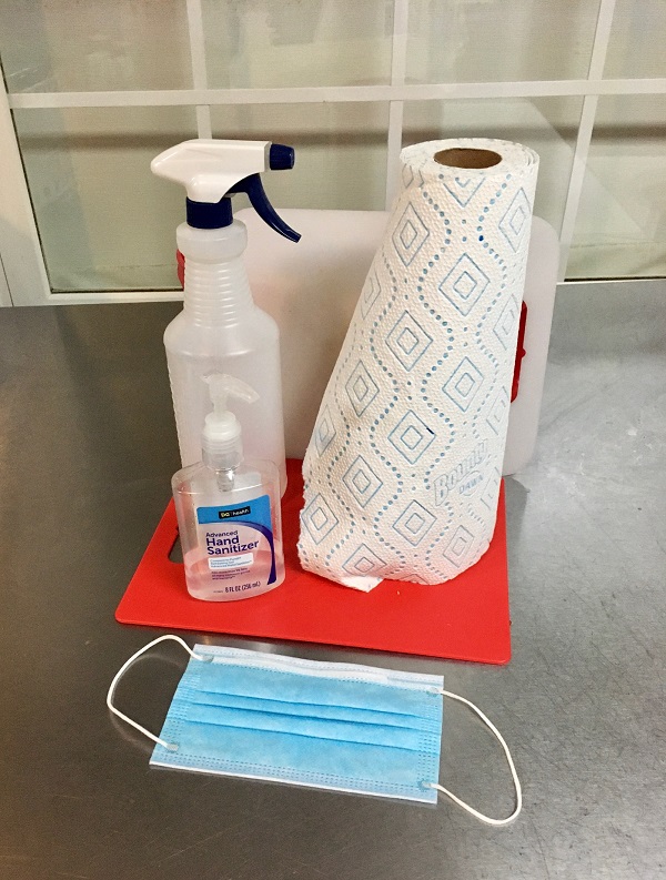 bottle with soap and water, paper towels, mask, hand sanitizer, cutting board in contrasting color