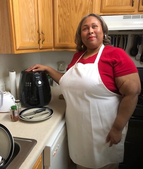 woman standing in kitchen with hand on top of air fryer