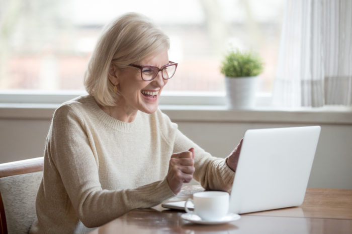 Senior woman smiling looking at laptop as if talking to someone