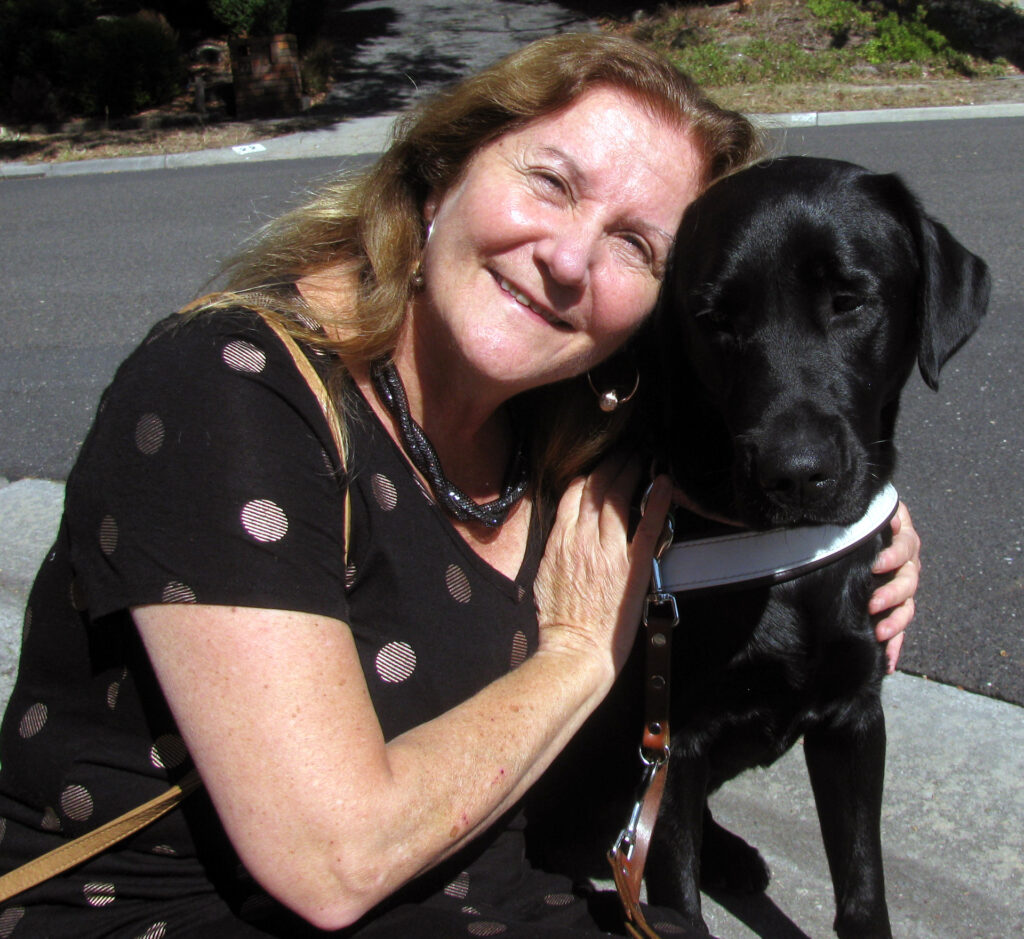 Maribel with her arms around Dindi, a small black lab