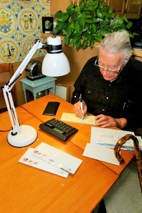 Man writing check at desk using desktop lamp
