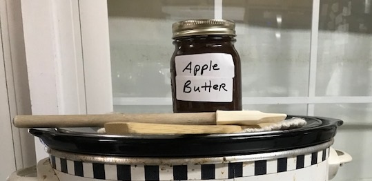 Jar of homemade apple butter sitting on top of crock pot