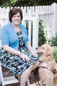 woman sitting with guide dog at her feet