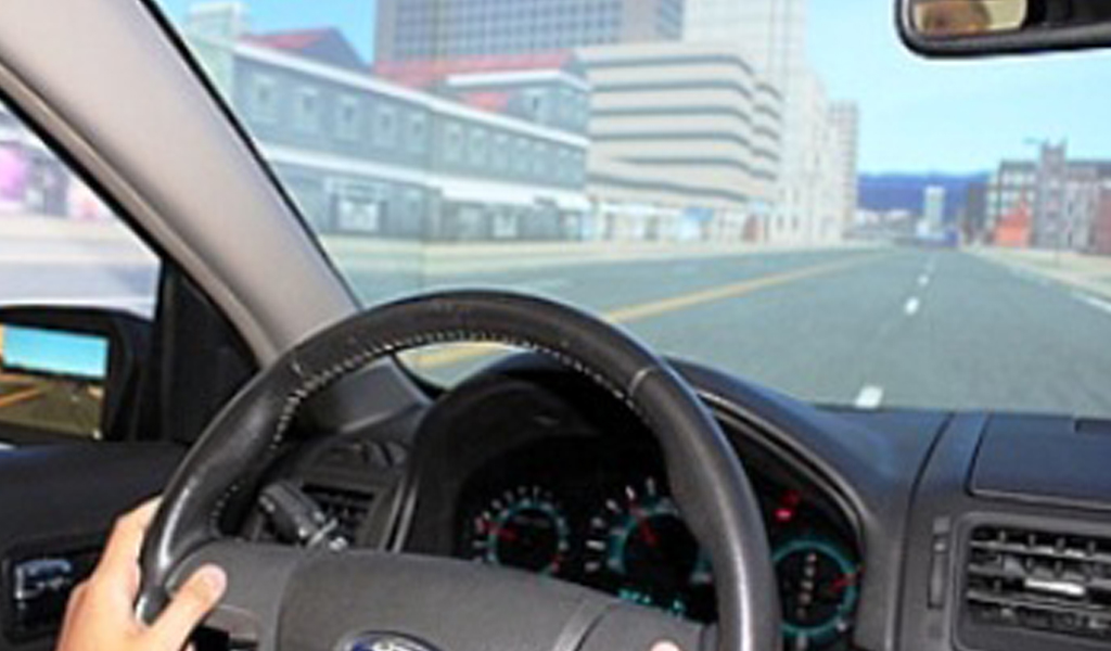 photo of hands on a steering wheel and the view of a street through the windshield of a car