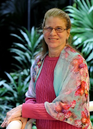 Elizabeth sitting in garden with plant fronds behind her