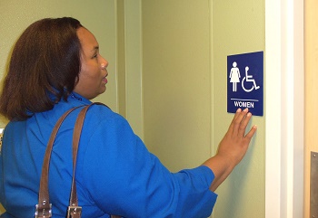 woman reading braille on women's bathroom sign