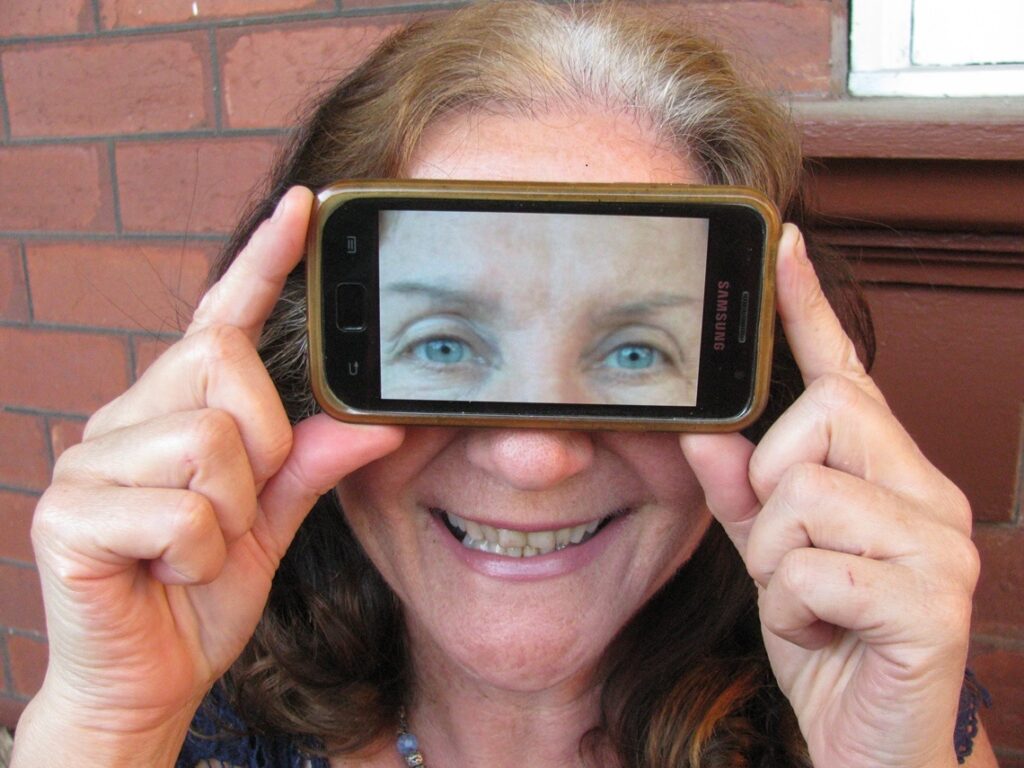 Maribel holding magnifier to her eyes. Photo by Harry Williamson
