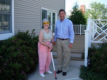 older woman with cane and son standing in front of house