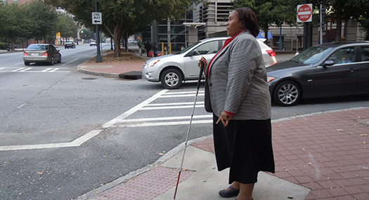 Empish using white cane to cross street