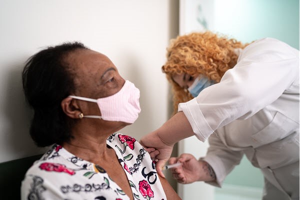 woman wearing mask, getting shot from health care provider. Image provided by CDC