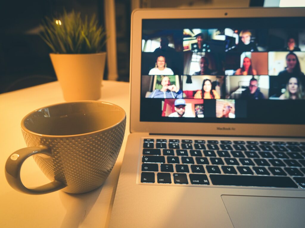 laptop computer with zoom group showing on screen and coffee cup sitting next to computer.Photo by Compare Fibre on Unsplash