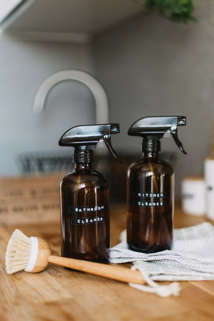 bottles of bathroom and kitchen cleaner with cleaning brush. Photo by Daiga Ellaby on Unsplash 