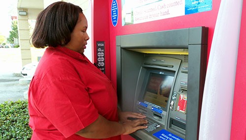 VisionAware Peer Advisor, Empish Thomas, using an ATM independently.
