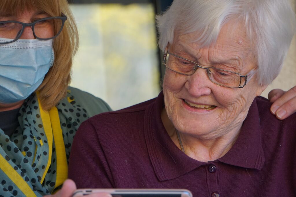 Senior Center Staff Member Standing Next to Older Participant with hand on their shoulder