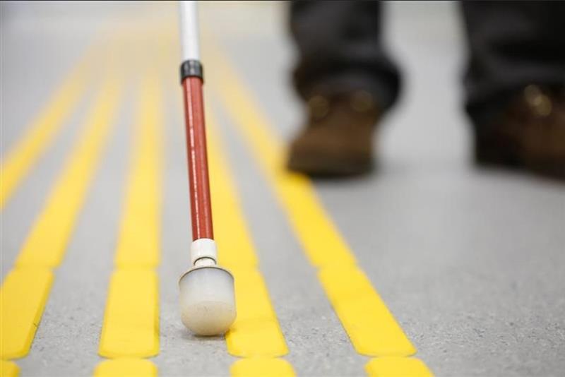 Tip of white Mobility Cane with red stripe being Used for Street Travel. 