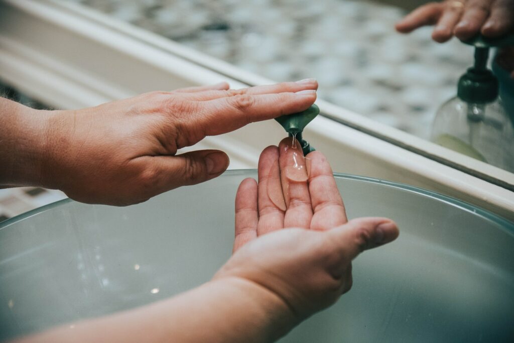 Person washing hands in sink. Photo by Jason Jarrach on Unsplash

