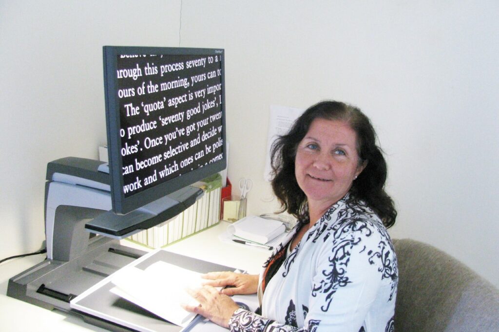 Maribel sitting in front of an electronic magnifier (CCTV)