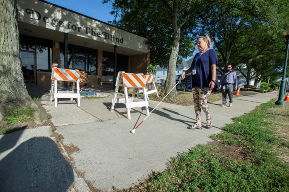 person using white cane to walk down sidewalk --photo provided by Guide Dogs for the Blind