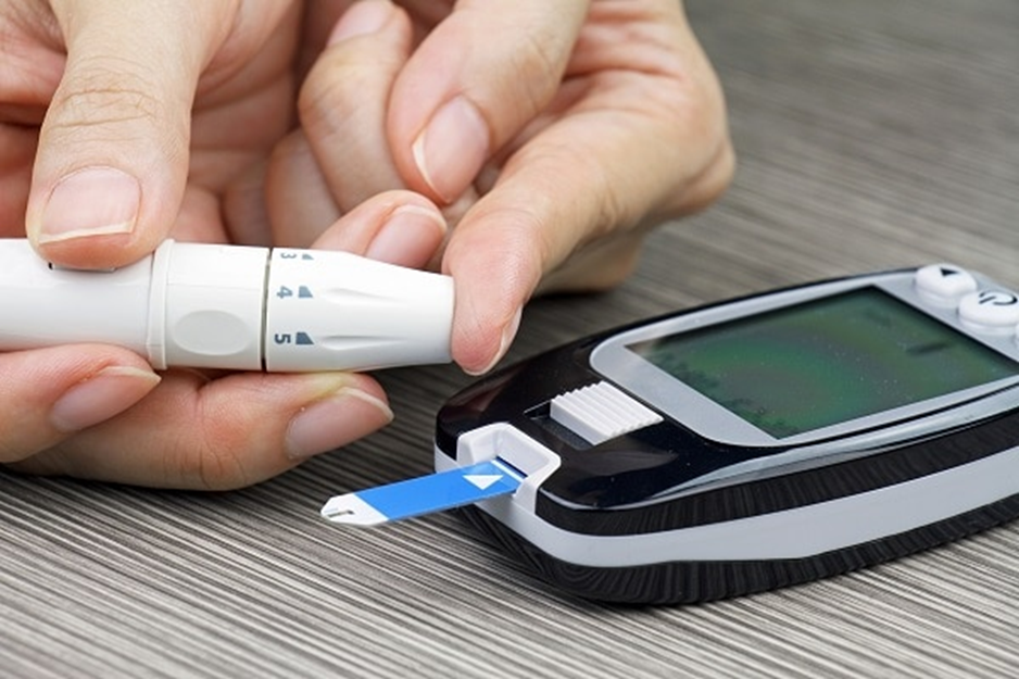 Photo of woman’s hand and blood glucose meter. She is pricking her finger. Compliments of NIH, NIDDK