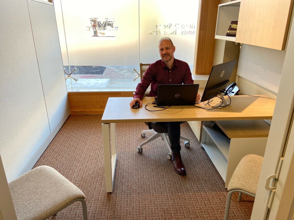 Lee Sitting at Desk Smiling