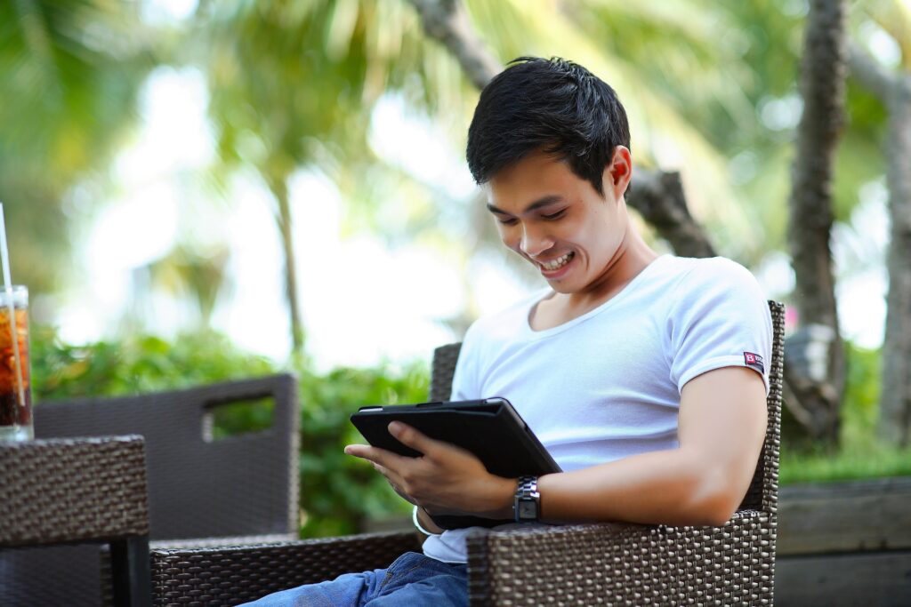 Individual Using Tablet While Seated on Park Bench